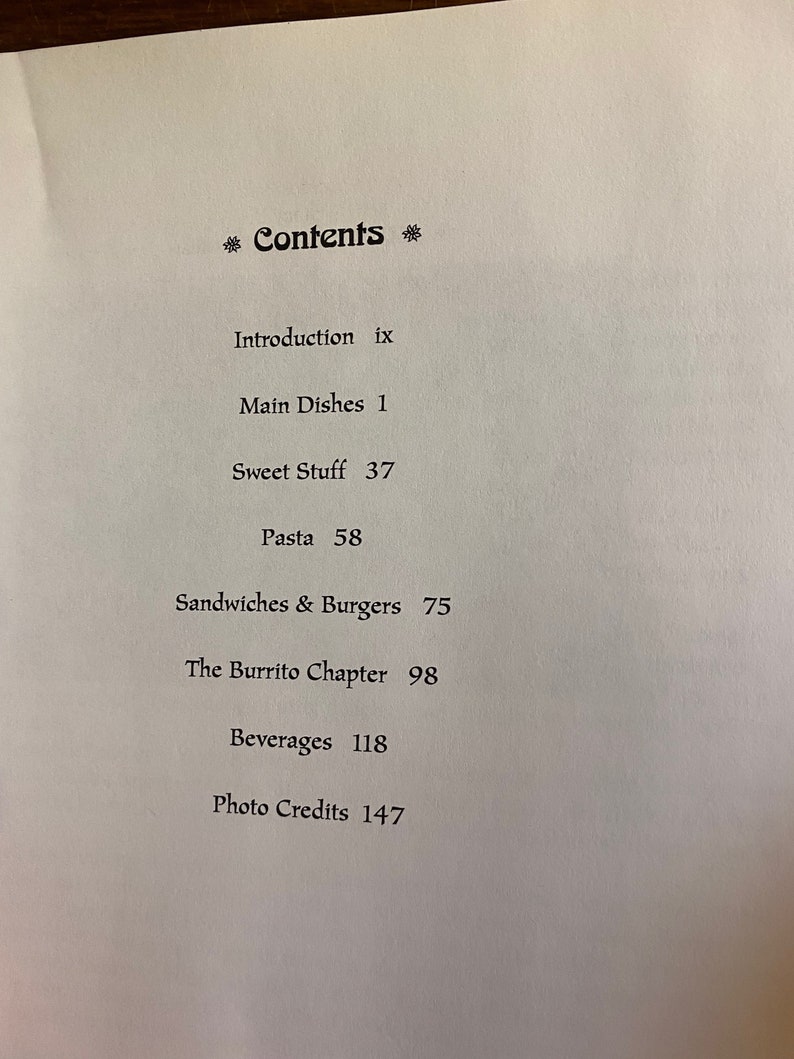 Puede incluir: Una p&aacute;gina en blanco y negro con la palabra "Contents" en negrita, seguida de una lista de t&iacute;tulos de cap&iacute;tulos y n&uacute;meros de p&aacute;gina. Los cap&iacute;tulos incluyen "Introduction", "Main Dishes", "Sweet Stuff", "Pasta", "Sandwiches & Burgers", "The Burrito Chapter", "Beverages" y "Photo Credits".