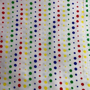 May include: White fabric with a repeating pattern of colorful polka dots. The dots are in red, yellow, green, and blue, arranged in vertical rows. The fabric has a slightly textured appearance.