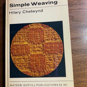 May include: A book titled "Simple Weaving" by Hilary Chetwynd. The cover displays a circular image of orange and yellow woven fabric on a dark blue backdrop. Published by Watson-Guptill Publications.