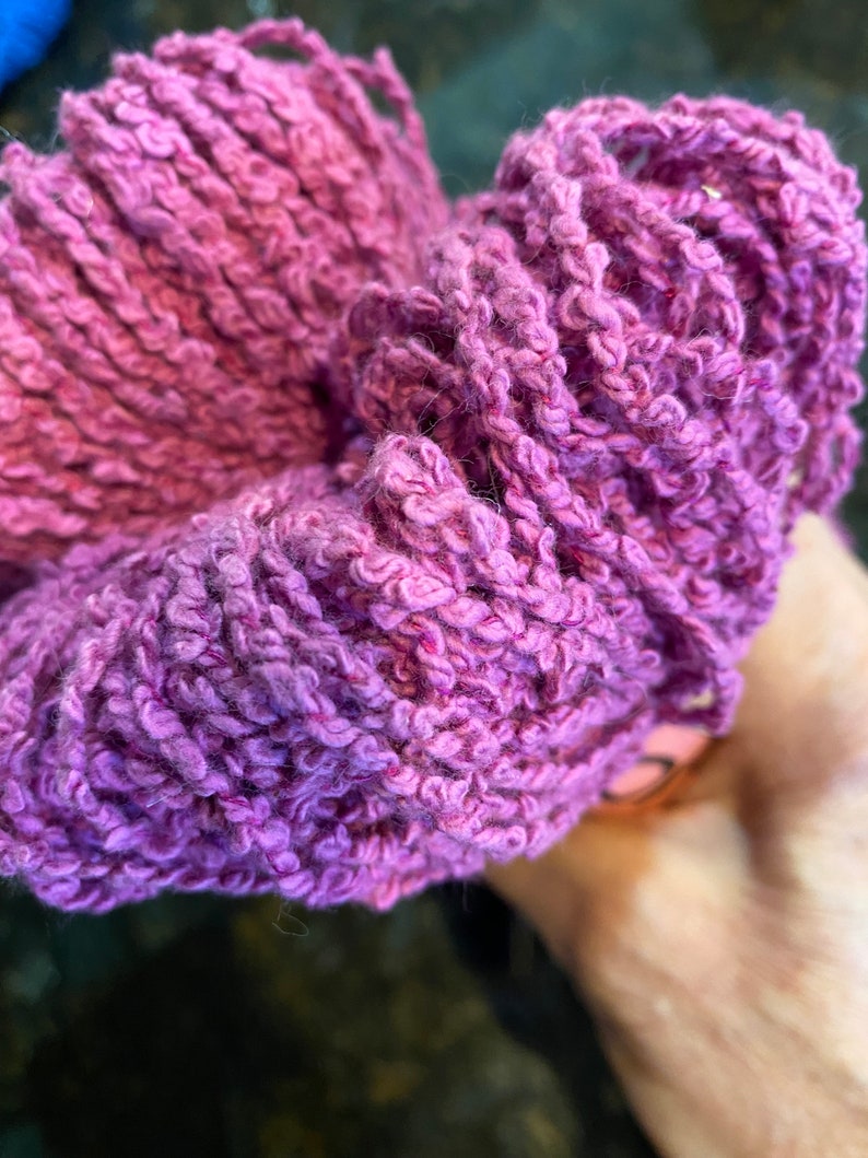 May include: A close-up of a purple yarn ball. The yarn is soft and fluffy, and it is perfect for knitting or crocheting.