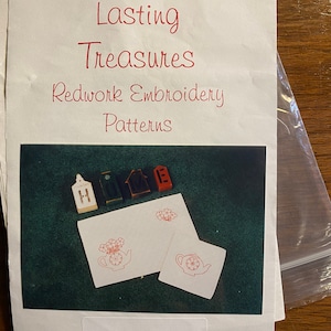 May include: A sheet of paper with the title "Lasting Treasures Redwork Embroidery Patterns" and a photo of two teapots with flowers embroidered on them. The text "Tea Pots" is at the bottom of the photo.