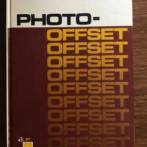 Puede incluir: Un libro color burdeos con el título "PHOTO-OFFSET" repetido en letras doradas. El libro es una "an publication" y tiene un lomo blanco.