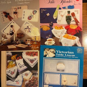 May include: Three counted cross stitch patterns for table linens. The first pattern is for placemats with a country heart theme. The second pattern is for table linens with a Victorian theme. The third pattern is for table linens with a fruit theme.