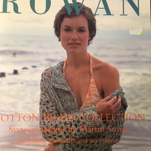 Pode incluir: Uma capa de livro com uma mulher de cabelo castanho curto vestindo um top de crochê e um top de biquíni de crochê. A capa do livro é intitulada "ROWAN COTTON BRAID COLLECTION Sixteen designs by Martin Storey including garments and accessories".