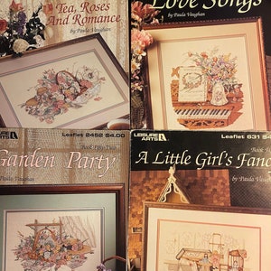 May include: Four framed cross-stitch patterns with floral and romantic themes. Titles include "Tea, Roses and Romance," "Love Songs," "Garden Party," and "A Little Girl's Fancy." Each features detailed needlework and decorative borders, perfect for craft enthusiasts.