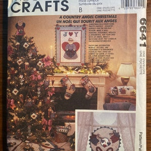 Puede incluir: Un patrón de costura vintage de McCall's Crafts para un tema navideño de ángel de campo. El patrón incluye instrucciones para hacer una decoración de pared, calcetines, una corona, adornos, un adorno para la cima del árbol, una falda y un buzón. La portada del patrón presenta una ilustración colorida de un árbol de Navidad decorado con ángeles, corazones y luces.