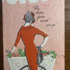 May include: Vintage-style greeting card featuring a woman in a red dress riding a bicycle with a flower basket. The card has the text "It's home from work we go" in a script font. The background is a soft pink.