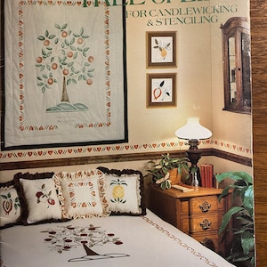 Puede incluir: Un libro titulado "Tree of Life" para el candlewicking y el esténcil. La portada presenta un fondo blanco con un marco de madera marrón y una imagen en stencil de un árbol con manzanas rojas. El libro está etiquetado como "Book #21".