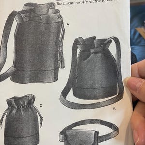 May include: A black and white illustration of four different bag designs. The bags include a drawstring bucket bag with a shoulder strap, a smaller drawstring bag, and a belt bag with a tassel. The text "FABU-LEATHER The Luxurious Alternative to Leather" is at the top.