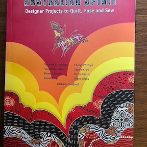 May include: A book titled "AUSTRALIAN SPIRIT" with the subtitle "Designer Projects to Quilt, Fuse and Sew." The cover features a butterfly illustration and a colorful, abstract design in red, orange, yellow, and black.