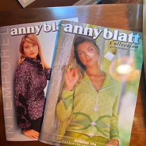 Può includere: Due riviste con il titolo "annyblatt" sulla copertina. La rivista a sinistra presenta una donna che indossa un maglione viola. La rivista a destra presenta una donna che indossa un maglione verde con un motivo floreale. Il testo sulla copertina della rivista a destra recita "Collection printemps-été" e "Numéro 194 Catalogue spécial couture".