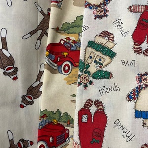 Könnte beinhalten: Drei Stoffbahnen mit unterschiedlichen Designs. Die erste Bahn zeigt ein sich wiederholendes Muster aus braunen Affen mit roten Nasen und weißen Socken. Die zweite Bahn zeigt ein rotes Feuerwehrauto mit einer weißen Kabine und einem gelben Hintergrund. Die dritte Bahn zeigt ein sich wiederholendes Muster aus Stoffpuppen mit roten, blauen und weißen Kleidern. Der Text "friends", "love" und "small" ist auf der dritten Bahn aufgedruckt.