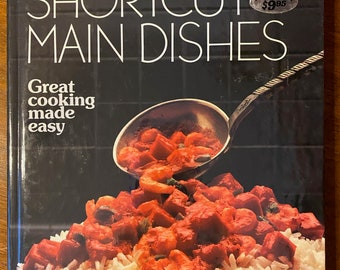 Puede incluir: Un libro de cocina titulado "Shortcut Main Dishes: Great cooking made easy" con una imagen de un plato de arroz cubierto con camarones y salsa roja.