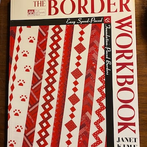 May include: A softcover book titled The Border Workbook by Janet Kime. The white cover features red and white quilt border patterns, including paw prints, diamonds, and zigzags. The text reads That Patchwork Place, Easy Speed-Pieced, and Foundation-Pieced Borders.