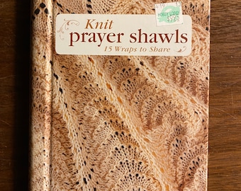 May include: A book titled "Knit prayer shawls" with a brown and beige knitted pattern on the cover. The book is a Leisure Arts Publication and has a price tag from Hobby Lobby for $9.25.