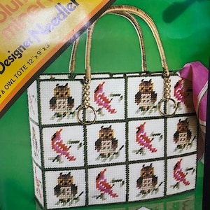 May include: A needlepoint tote bag with a design of owls and cardinals. The bag has a brown wicker handle and a gold chain with a key ring. The bag is 12 inches by 9 inches by 3 inches.