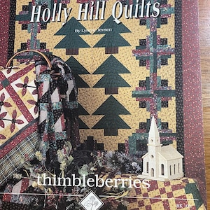 May include: The cover of a book, "Holly Hill Quilts" by Lynette Jensen, shows a quilt design with green Christmas trees on a yellow backdrop. The word "thimbleberries" is visible, along with a small wooden church.