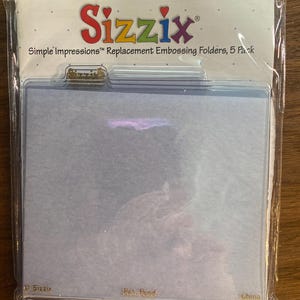 May include: A package of Sizzix Simple Impressions replacement embossing folders. The package is clear plastic, and the product is visible inside. The Sizzix logo is in red and white. The package also says "5 Pack".
