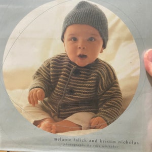 May include: A book titled "Knitting for Baby" with 30 heirloom projects and complete how-to-knit instructions. The cover features a photo of a baby wearing a blue knitted hat and a striped sweater.