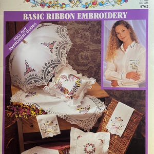 Könnte beinhalten: Ein Simplicity-Schnittmuster für die grundlegende Bandstickerei. Das Cover zeigt einen weißen Sonnenschirm, Kissen und Leinen mit floralen Stickereien. Das Bild zeigt auch eine Frau, die ein weißes Hemd mit gestickten Details trägt.