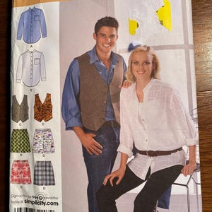 May include: A sewing pattern for a shirt, vest, and shorts. The pattern is from Simplicity and is easy-to-sew. The pattern includes instructions for making a blue shirt, a brown vest, and a pair of green and white patterned shorts.