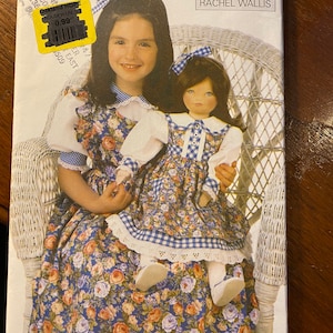 Puede incluir: Un patrón de costura vintage para un vestido de niña, con estampado floral y ribete de vichy. El patrón es de Butterick y diseñado por Rachel Wallis. El número del patrón es 6372.