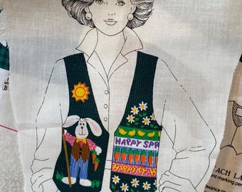 May include: A white fabric panel with a black line drawing of a woman wearing a green vest with a sun, bunny, and carrots design. The vest has a tie with the words "Happy Spring" and a carrot design. The fabric panel has a label that says "Attach Label".