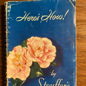 Puede incluir: Un libro de cocina azul con el título "Here's How!" de Stouffer's. La portada presenta dos flores de camelia rosas.