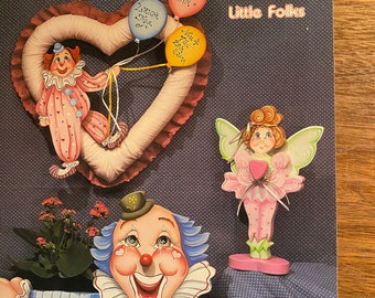 May include: A book titled "Happy Strokes for Little Folks" by Rhonda Williams. The cover features illustrations of a clown, a fairy, and a heart-shaped wreath with balloons that say "It's a Girl!" and "Zara June 2002".