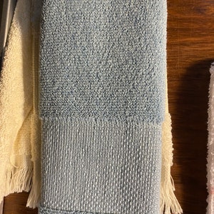 May include: A folded blue and white striped towel with a textured surface.