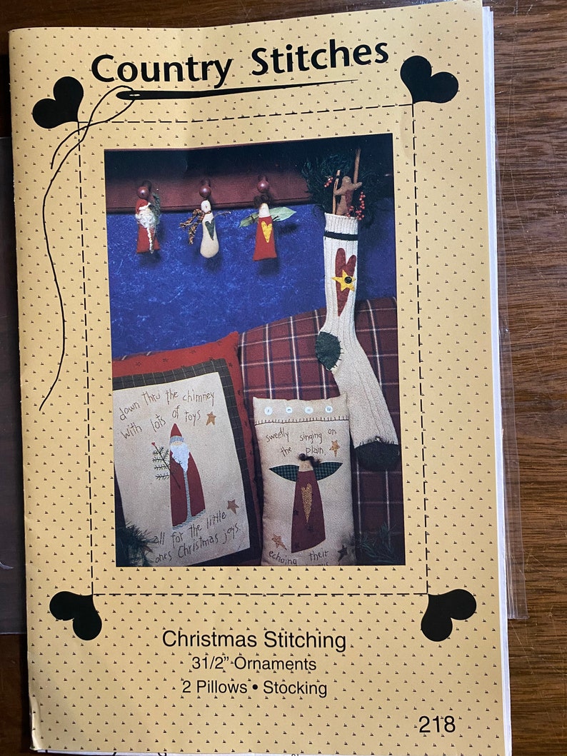 May include: A craft pattern for Christmas stitching, featuring a stocking, two pillows, and three ornaments. The pattern includes the text "down the chimney with lots of toys" and "all for the little ones Christmas joys".