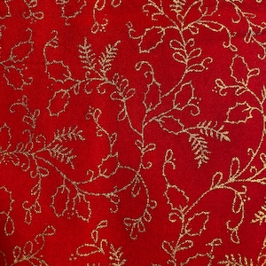 May include: Red fabric with a gold floral pattern. The pattern features leaves and vines.