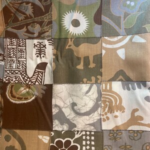 Peut inclure: Un patchwork en tissu composé de divers carrés aux motifs imprimés dans des tons marron, vert olive, beige et crème. Les motifs incluent des fleurs stylisées, un soleil, une silhouette d'animal et des formes géométriques variées.