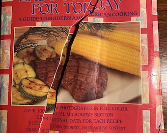 Puede incluir: Un libro de cocina rojo titulado "Easy Cooking for Today: A Guide to Modern American Cooking" con una portada rasgada. La portada presenta una foto de maíz asado en la mazorca y un bistec con calabacín.