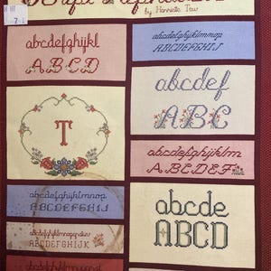 May include: A cross-stitch sampler showcasing diverse script alphabets in various styles and colours. The title "Script Alphabets" is displayed at the top, with the author's name below. The sampler includes both uppercase and lowercase letters.