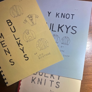 Könnte beinhalten: Ein Stapel Vintage-Strickmusterhefte. Die Hefte zeigen Illustrationen von Pullovern und den Text "BULKYS MEN'S", "Y KNOT BULKYS" und "BULKY KNITS" von Lois Blystone. Die Hefte sind in Gelb, Blau und Off-White gehalten.