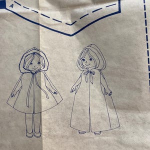 May include: A sewing pattern featuring two illustrations of children's capes. One cape has a fur-lined hood, and the other has a simple hood. Both illustrations are in blue ink on a cream-colored background.