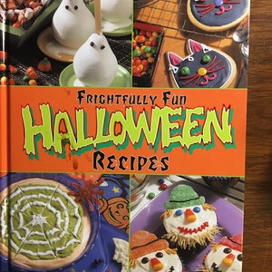 May include: A cookbook titled "Frightfully Fun Halloween Recipes" with a bright orange cover and colorful images of Halloween-themed treats, including ghost-shaped desserts, spiderweb dip, and cupcakes decorated as scarecrows.