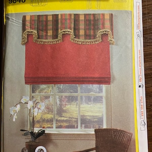 May include: Simplicity pattern number 9848 for a window treatment. The pattern includes instructions for a red plaid valance with a scalloped edge and a red roman shade. The image shows the finished window treatment in a room with a wicker chair and a potted orchid.