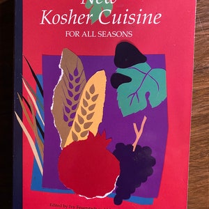 Peut inclure: Une couverture de livre rouge avec le titre "Nouvelle cuisine casher pour toutes les saisons". La couverture présente une illustration colorée d'une grenade, de raisins, de blé et de feuilles.