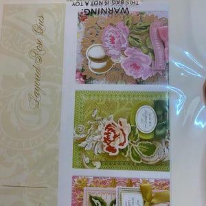 Może przedstawiać: Opakowanie warstwowych wykrojnik&oacute;w r&oacute;ż do rękodzieła. Obraz przedstawia trzy przykładowe projekty kart z kompozycjami kwiatowymi, w tym r&oacute;żowe i ż&oacute;łte r&oacute;że, dekoracyjne ramki oraz tekst "Happy Birthday" i "Thinking of You".