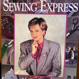 Puede incluir: Portada del libro "Sewing Express" de Nancy Zieman. La imagen muestra a una mujer con una camisa rosa y una blazer gris. También se ven herramientas de costura como tijeras, carretes de hilo y alfileres.