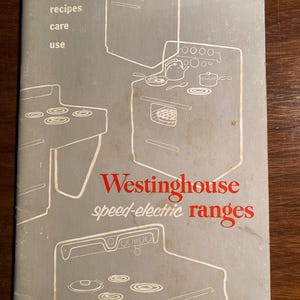Può includere: Un libro di cucina vintage Westinghouse per forni elettrici a velocità con illustrazioni di diverse caratteristiche del piano cottura e del forno. La copertina è grigia con testo rosso e disegni a linea nera.