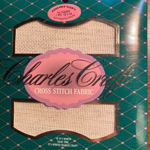 Peut inclure: Un paquet de tissu pour point de croix Charles Craft. Le tissu est blanc et a un compte de 14. L'emballage est vert avec un motif rose et or. Le texte sur l'emballage indique "Fiddler's "Lite" 14 Count 1 PC. 12 x 18 Cotton/Poly/Flax" et "Charles Craft Cross Stitch Fabric" et "If it's worth your time, it's worth Charles Craft."