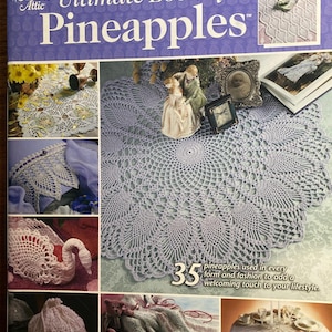 May include: The cover of a crochet book, "Annie's Attic Ultimate Book of Pineapples", displays various crochet projects. The image includes a large, detailed doily and other pineapple-themed designs. The book features 35 pineapple patterns.