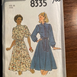 May include: Simplicity sewing pattern number 8335 for a dress. The pattern is for size 10 miss. The pattern shows two different styles of dresses, one with a floral print and one in a solid blue colour. The pattern is priced at £2.00.
