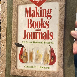 Op de afbeelding: Een boek getiteld "Making Books and Journals" van Constance E. Richards. De omslag heeft een kader met rode tekst en illustraties van peren. Het boek maakt deel uit van de serie "The Weekend Crafter".
