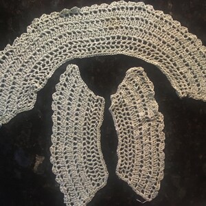 May include: Three pieces of crocheted lace in a light green color. The lace is in the shape of a collar and two smaller pieces.