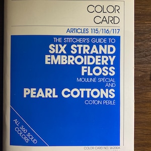 May include: A white DMC color card featuring blue text and graphics. The cover reads: DMC COLOR CARD ARTICLES 115/116/117 THE STITCHER'S GUIDE TO SIX STRAND EMBROIDERY FLOSS MOULINÉ SPÉCIAL AND PEARL COTTONS COTON PERLÉ ALL 360 SOLID COLORS W-200A 1990-1.