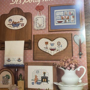 May include: A collection of framed cross-stitch samplers with a bathroom theme, including a heart-shaped frame and a towel rack. The artwork features teddy bears and bathroom scenes. The title "It's Potty Time #2" is visible.